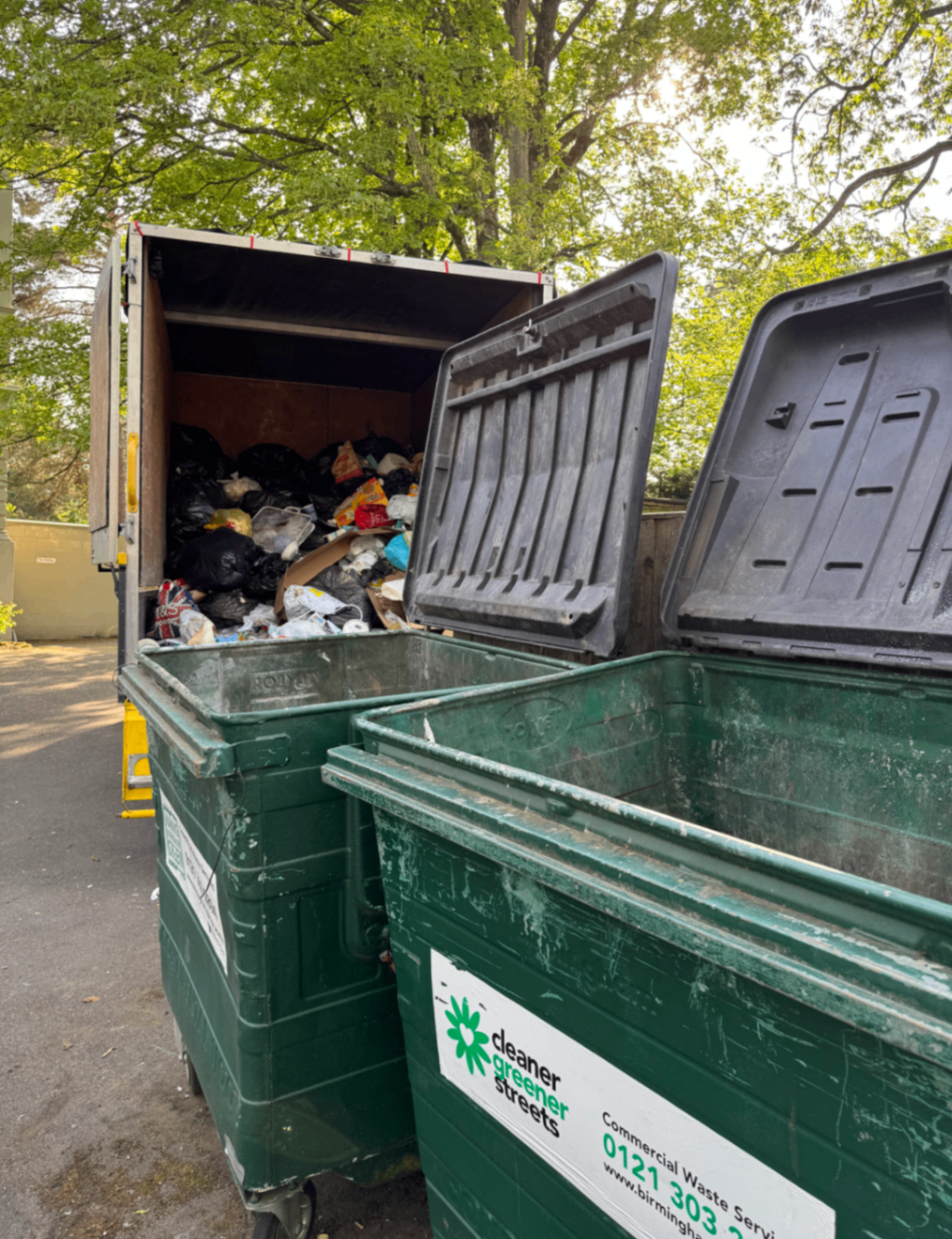 Commercial bin collection with a loaded truck parked behind open wheelie bins